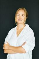 Studio portrait of beautiful confident woman posing on black background, wearing white shirt photo