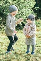 Outdoor portrait of little preschool brother trying to cheer up shy toddler sister photo