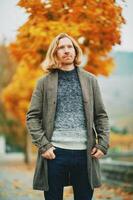 Outdoor portrait of young red haired man, wearing pullover and coat, cold foggy day photo