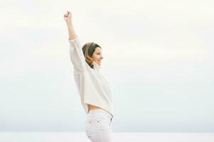 Outdoor portrait of happy strong and confident woman with her fist up in the air photo
