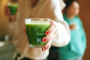 mujer proponiendo vaso con verde linfa tónico vitamina aumentador de presión beber, cerca arriba imagen foto