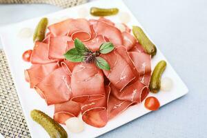 Plate with air-dried beef decorated with mint leaf photo