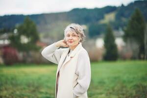 Outdoor portrait of beautiful middle age woman, wearing white coat photo