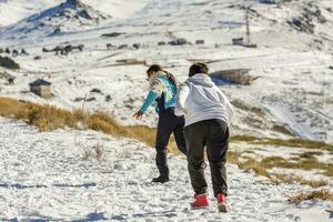 Latin boys running through the snow on a sunny day in the mountains photo