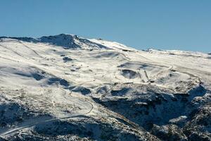 panoramic view of ski resort in sierra nevada, skiers along the slopes photo