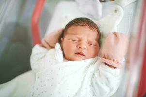 Portrait of adorable newborn baby lying in hospital crib photo