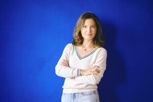 Portrait of pretty 40 year old woman posing next to bright blue wall photo