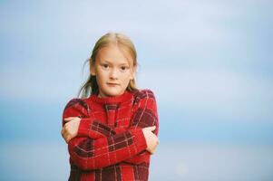 Outdoor portrait of beautiful little girl wearing red sweater, showing cold sign photo