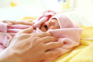 recién nacido bebé cubierto en toalla después tomando bañera foto