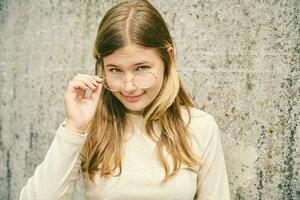 Outdoor portrait of young happy teenager girl wearing glasses photo