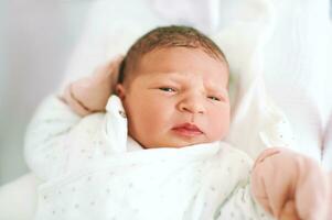 Portrait of adorable newborn baby lying in hospital crib photo