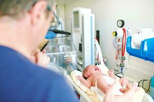 Crying newborn baby on weight scale in hospital, first days of life photo