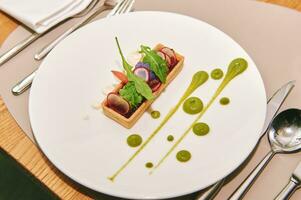 Tartlet with colorful vegetables decorated with green sauce photo