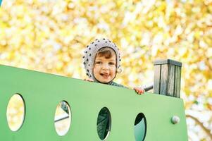 Outdoor portrait of happy smiling toddler girl having fun on playground, cold weather photo