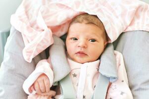 Funny newborn baby sitting in high chair photo