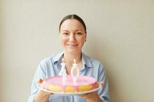 Happy middle age 40 year old woman holding cake with candles photo