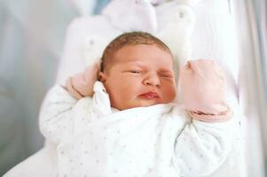 Portrait of adorable newborn baby lying in hospital crib photo