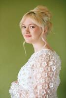 Beauty portrait of pretty young 15 - 16 year old teeenage girl wearing white dress posing on green background photo