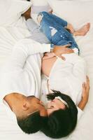 Top view of young pregnant couple cuddling in bed photo