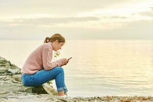 Outdoor portrait of young teenage girl listening music next to lake or sea, image taken in Lausanne, Switzerland photo