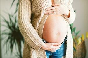 cerca arriba imagen de embarazada barriga, joven mujer participación bebé bache foto