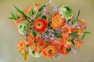 Flat lay image of green and orange ranunculus and alstroemeria bouquet photo