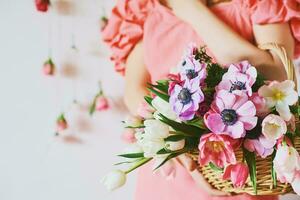 Woman holding basket with many colorful flowers, spring background photo