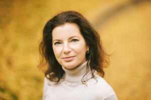 Autumn portrait of beautiful mature woman, relaxing in golden fall park photo