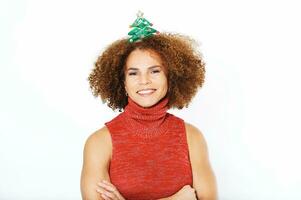 estudio retrato de contento hermosa medio años mujer Listo a celebrar Navidad y nuevo año, posando en blanco fondo, vistiendo rojo vestido, dama con Navidad regalo venda foto