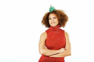 estudio retrato de contento hermosa medio años mujer Listo a celebrar Navidad y nuevo año, posando en blanco fondo, vistiendo rojo vestido, dama con Navidad regalo venda foto