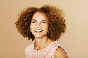 Fashion studio portrait of stylish middle age woman posing on beige background, smiling 50 - 55 year old lady with curly hair photo