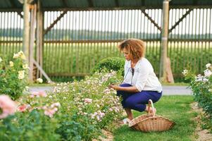 Outdoor portrait of beautiful 50 year old woman enjoying nice day in flower park or garden, happy and healthy lifestyle photo