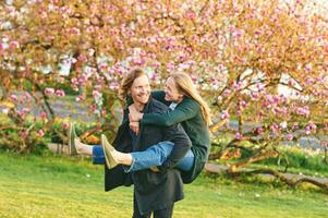 Outdoor portrait of happy romantic couple, woman sitting on back of her boyfriend, happy relationships photo