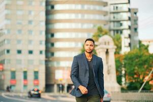 Outdoor portrait of handsome afro american man, city landscape on background photo