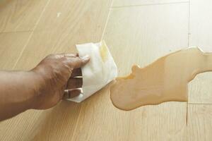 hand wiping spilled tea with paper napkin on floor , photo