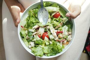 parte superior ver de mujer participación un cuenco de Fresco ensalada a hogar foto