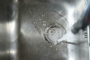 Water dripping from faucet tap at kitchen. Closeup photo