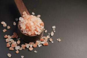 Raw dried pink Himalayan salt on wooden spoon photo