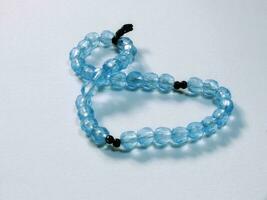 Aquatic blue prayer beads with 33 knots made of crystal clear beads isolated on a white background photo