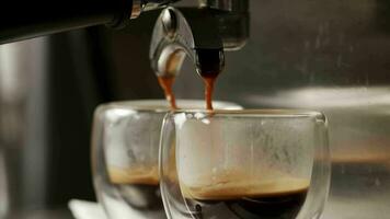 gieten een koffie Jet van een professioneel machine in een beker. een Mens barista maakt een espresso gebruik makend van de filter houder. vers grond koffie stromen. drinken geroosterd zwart koffie in de ochtend- video