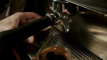 gieten een koffie Jet van een professioneel machine in een beker. een Mens barista maakt een espresso gebruik makend van de filter houder. vers grond koffie stromen. drinken geroosterd zwart koffie in de ochtend- video