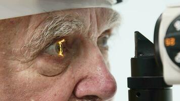 Close-up of a senior man having his vision tested on an ophthalmology diagnostic vision testing equipment. Old man doing eye test with non contact tonometer, checking vision at optical clinic video