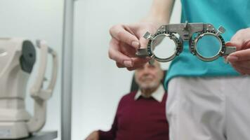 Augenarzt macht ein Auswahl von Linsen, Diagnosen ein Alten Senior des Mannes Vision auf ein Zeichen Beamer. das Konzept von testen und Vision Korrektur mit Neu medizinisch Technologien. video