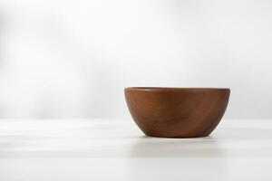 A vacant wooden bowl on the table and a white background in the morning. photo