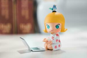 The yellow-haired girl doll is meditating with a yellow laptop computer and a blue bird on her head. Molly doll photo