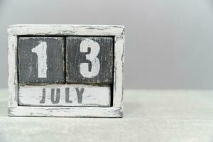 Calendar for July 13, made of wooden cubes, on gray background.With an empty space for your text. photo