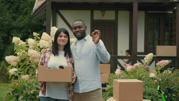 portret van een Afrikaanse man en Kaukasisch vrouw met dozen in hun handen terwijl in beweging naar een nieuw huis. video