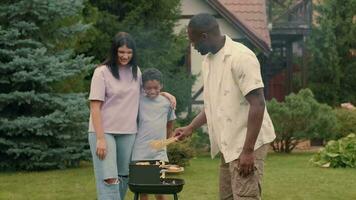 een Afrikaanse vader kookt rooster groenten voor zijn multi-etnisch familie. video