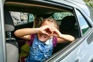 pequeño divertido niña velocidades en coche cerca el abierto ventana foto