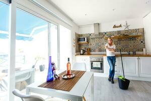 Cleaning concept. Young woman washing floor on the kitchen photo